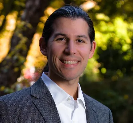 A man wearing a suit and tie smiling for the camera.