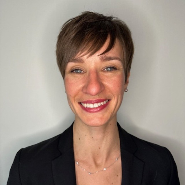 A woman with short hair and a necklace smiling.