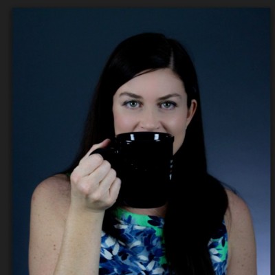 A woman with a black coffee cup and a blue and white floral top.